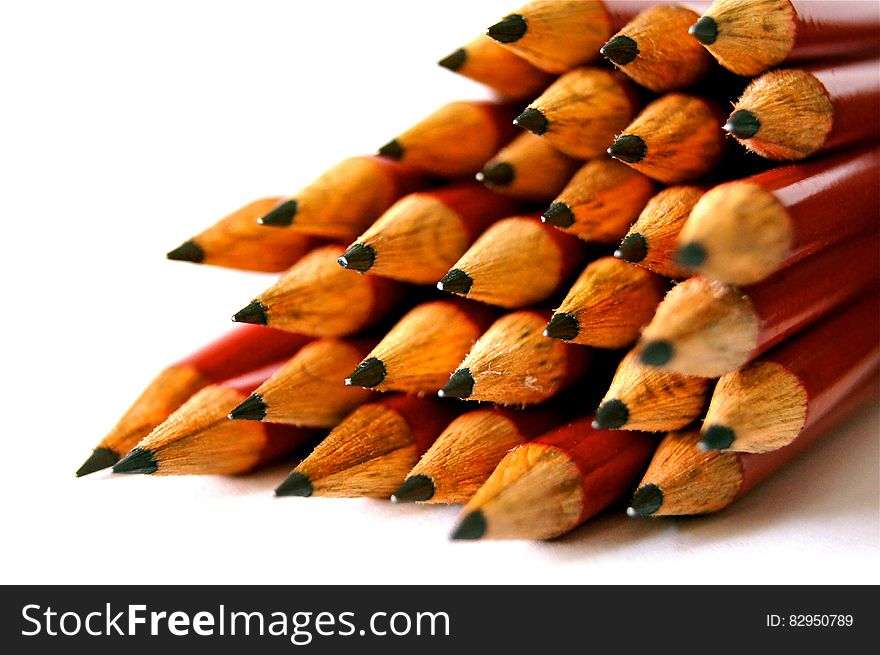 Pile of red wooden pencils with sharpened tips on white. Pile of red wooden pencils with sharpened tips on white.