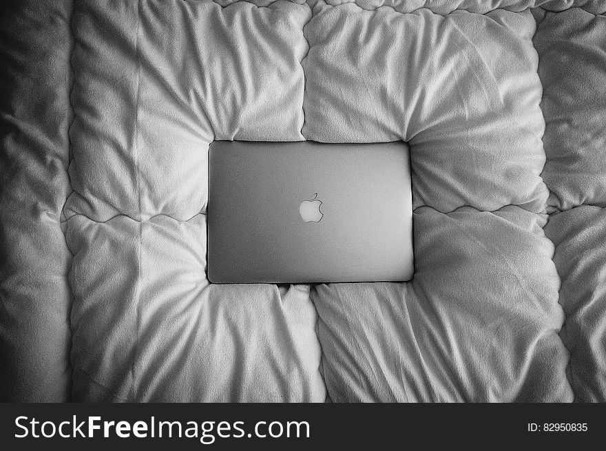 Apple Macbook laptop computer on bedspread in black and white.