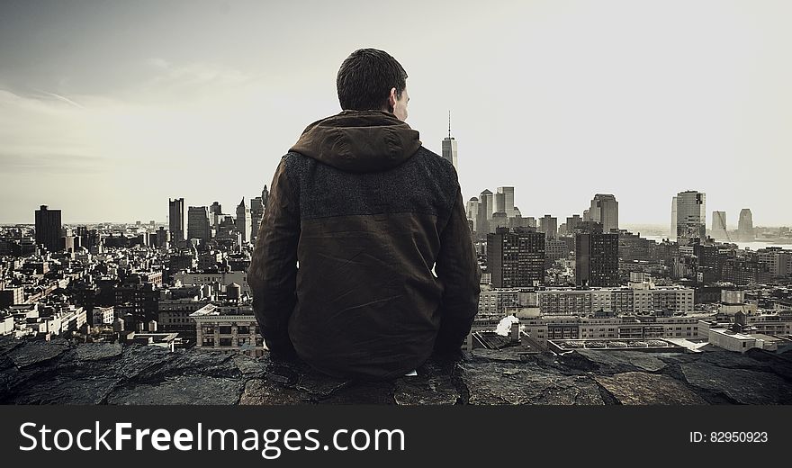 Man standing on rooftop overlooking urban skyline and waterfront. Man standing on rooftop overlooking urban skyline and waterfront.