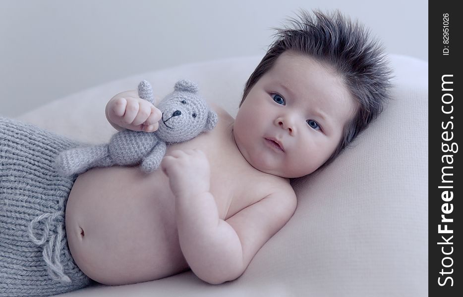 Studio portrait of Asian infant boy holding knit teddy bear. Studio portrait of Asian infant boy holding knit teddy bear.