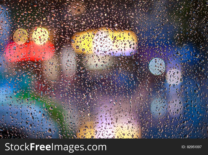 A surface with rain drops on it with defocused lights behind it. A surface with rain drops on it with defocused lights behind it.