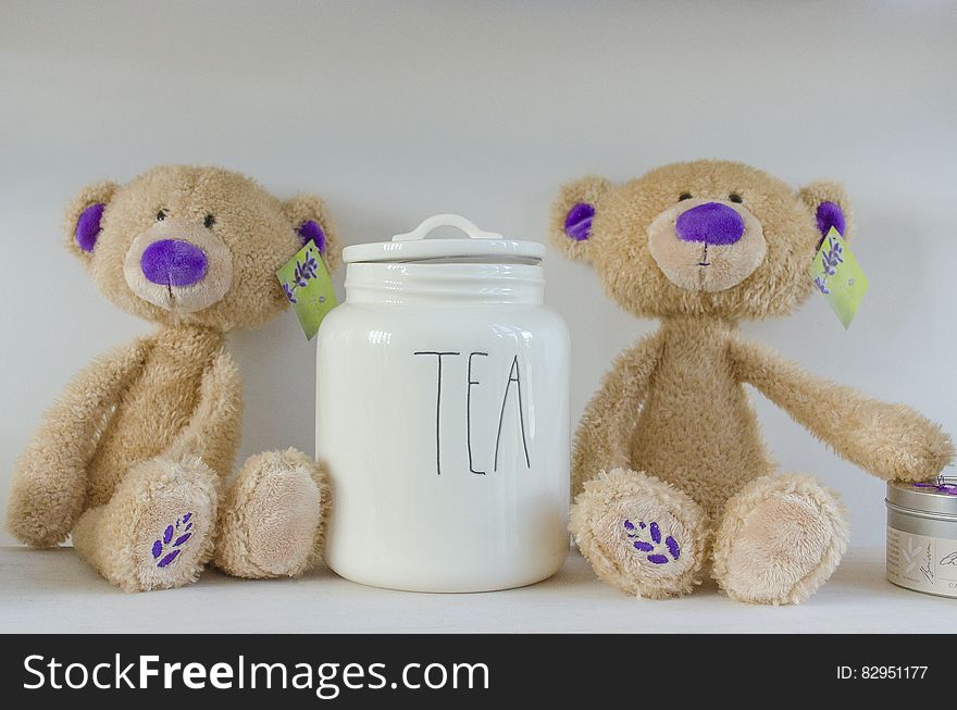 Pair of teddy bears on shelf with white china canister labeled tea. Pair of teddy bears on shelf with white china canister labeled tea.