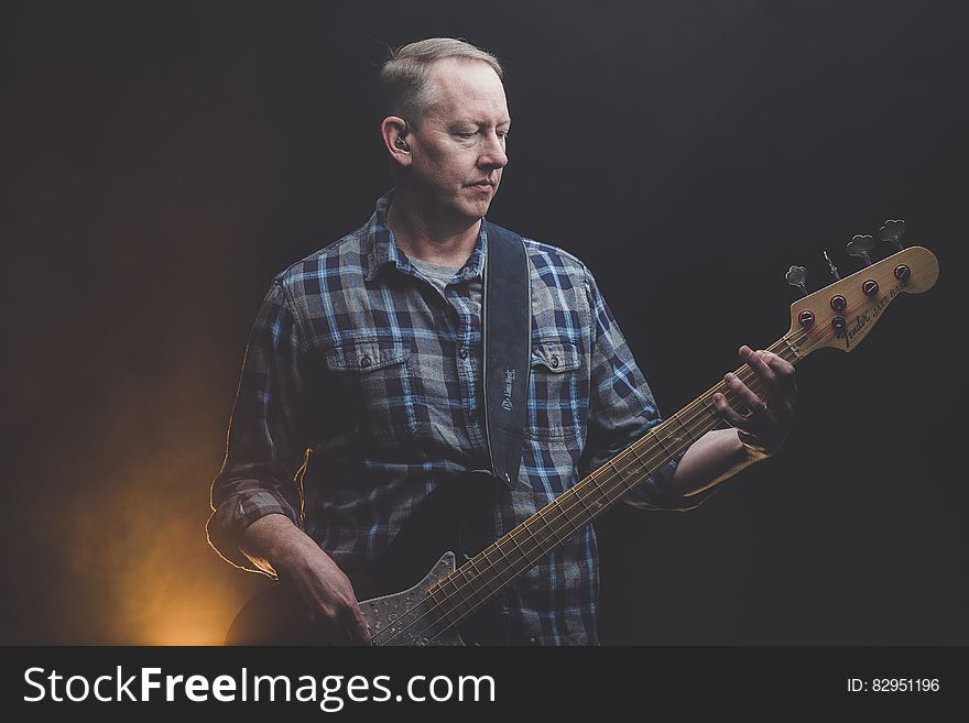 A man with a bass guitar on a stage. A man with a bass guitar on a stage.