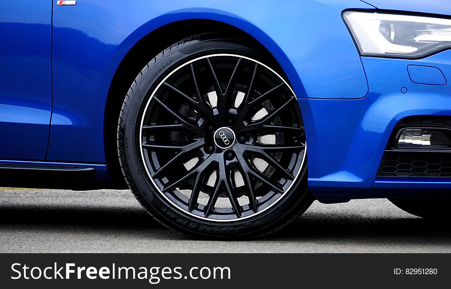 Close up of tire and front section of blue Audi luxury car. Close up of tire and front section of blue Audi luxury car.