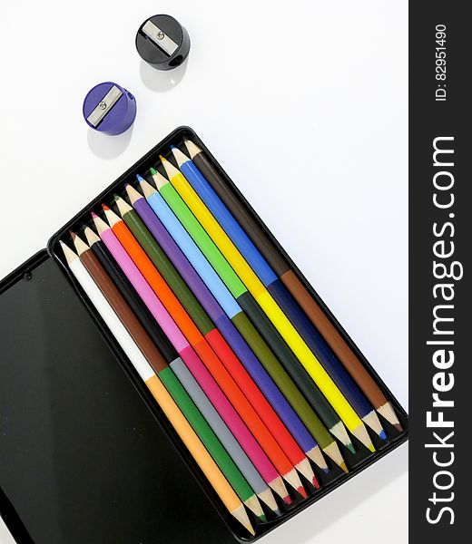 Black case with colorful pencils and sharpeners on white. Black case with colorful pencils and sharpeners on white.