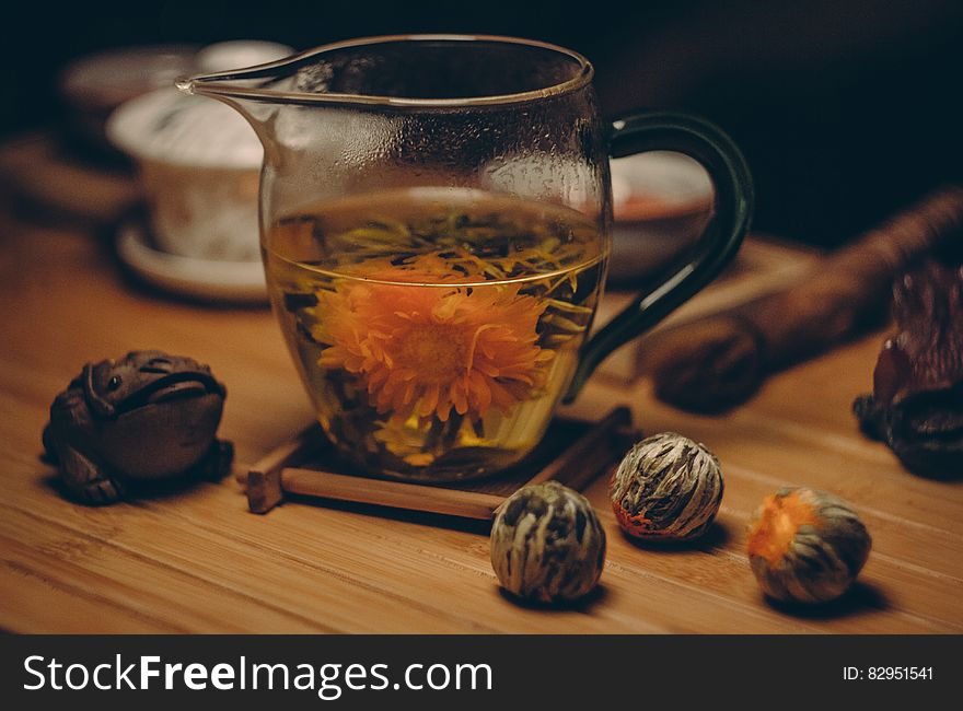 Orange Petaled Flowers In Clear Glass Pitcher With Water On Brown Table Close Up Photography