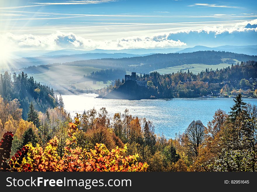 Autumn foliage in forest along lake with blue skies and clouds. Autumn foliage in forest along lake with blue skies and clouds.