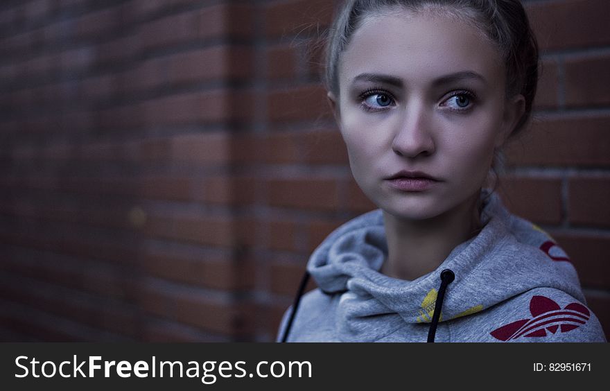 Macro Shot of Woman in Gray Adidas Pull over Hoodie Near Brick Wall
