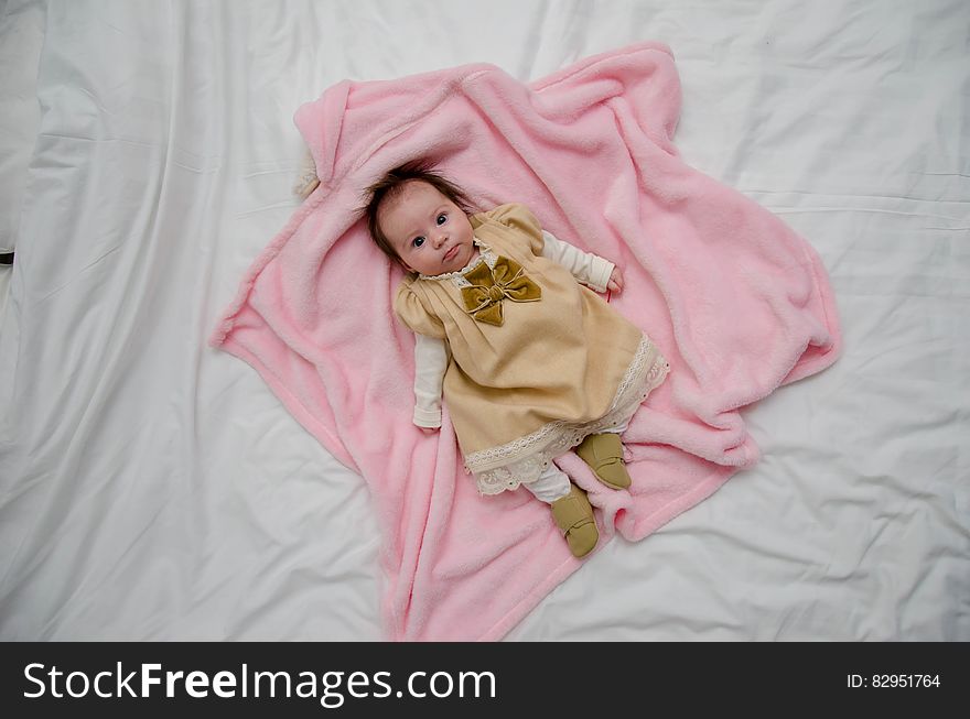 Baby in White and Yellow Dress on Pink Textile