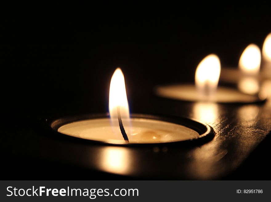 Lit tea candles isolated on black.