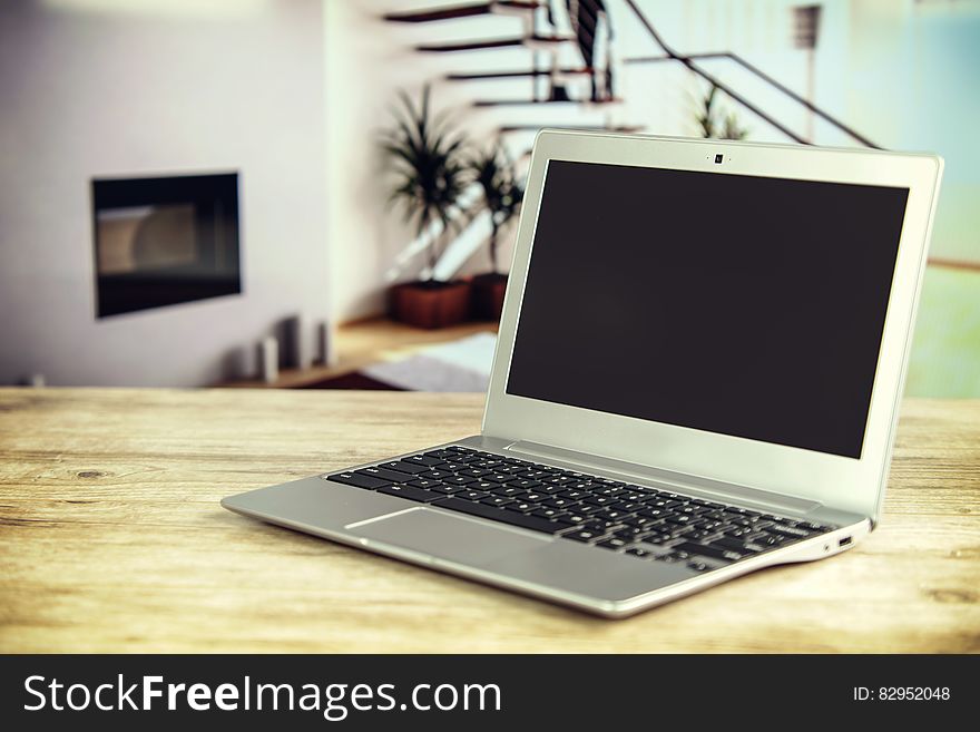 Laptop computer open on wooden table inside home. Laptop computer open on wooden table inside home.