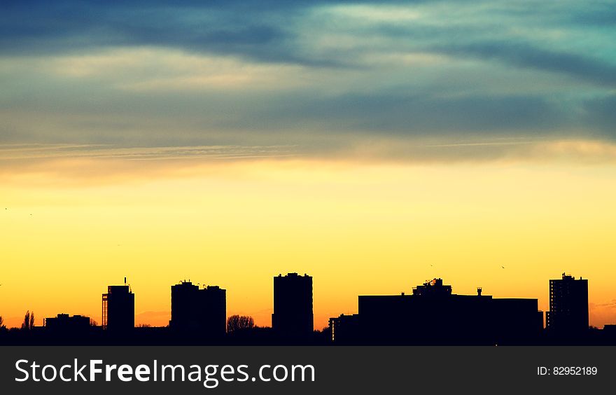 Silhouette of urban skyline against orange and blue skies at sunset. Silhouette of urban skyline against orange and blue skies at sunset.