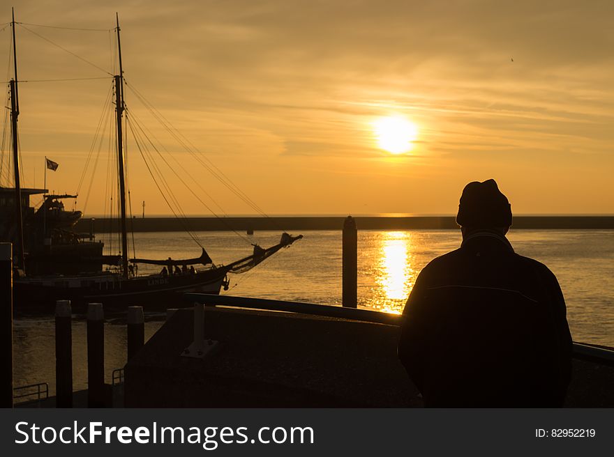 Person Standing on Dock during Sunset