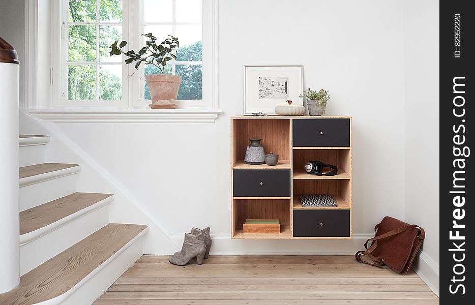 Stairway with boots and briefcase next to shelves inside modern home on sunny day. Stairway with boots and briefcase next to shelves inside modern home on sunny day.