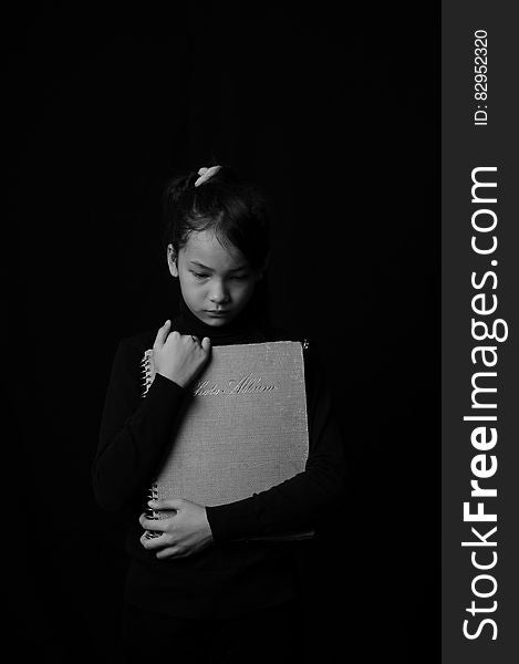 Portrait of young girl holding schoolbook in black and white. Portrait of young girl holding schoolbook in black and white.