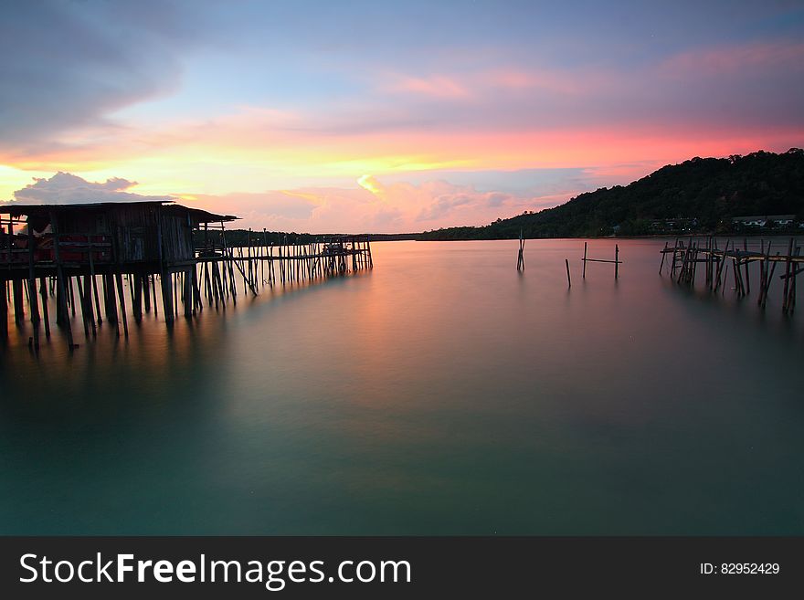 Wooden pier on coastline at sunset with pink skies. Wooden pier on coastline at sunset with pink skies.
