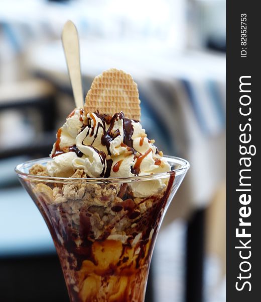 Chocolate ice cream sundae in glass with spoon and wafer.