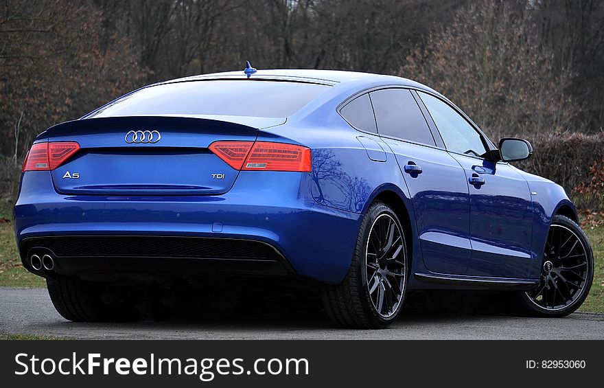 Blue Audi sports coupe on roadway from behind. Blue Audi sports coupe on roadway from behind.