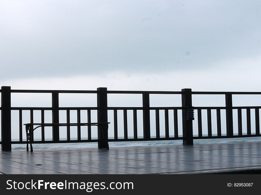 Wooden waterfront dock or boardwalk with railing against cloudy skies. Wooden waterfront dock or boardwalk with railing against cloudy skies.