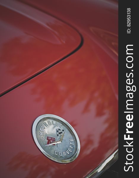 Close up of Chevrolet Corvette logo on hood or trunk of red sports car.