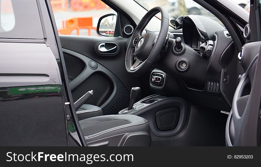 Black leather steering wheel and dash in interior of luxury car outdoors. Black leather steering wheel and dash in interior of luxury car outdoors.