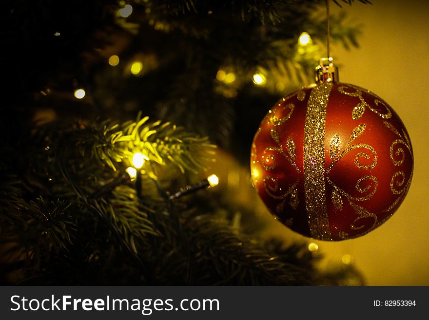 Red and gold Christmas ornament on tree with lights. Red and gold Christmas ornament on tree with lights.