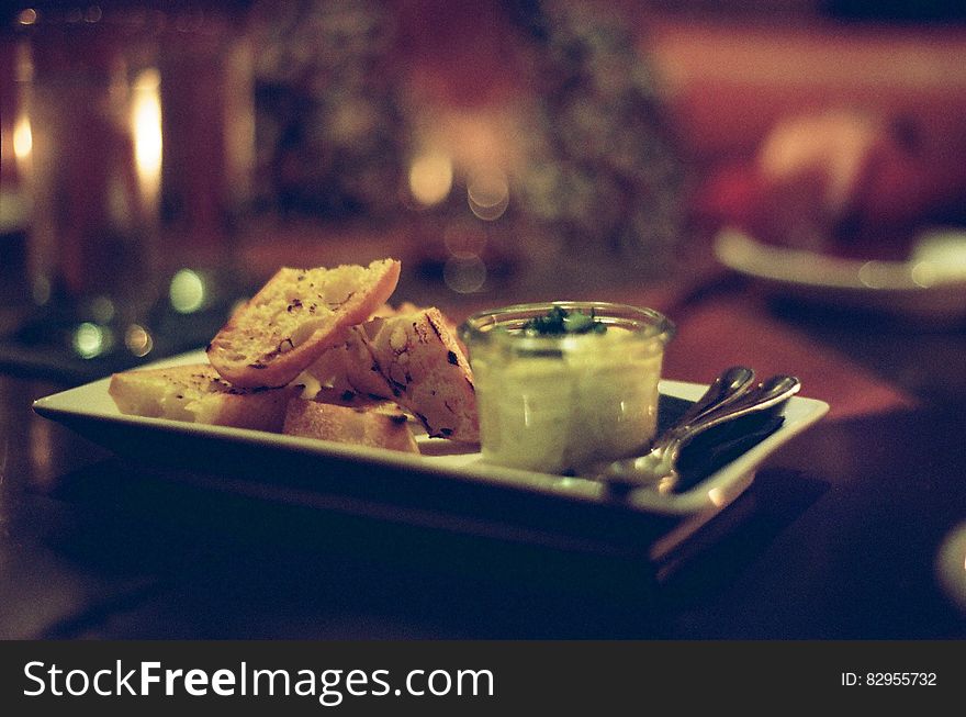 Restaurant tabletop with white china plate of toasted bread and dip appetizer. Restaurant tabletop with white china plate of toasted bread and dip appetizer.