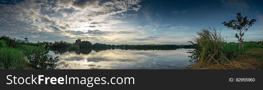 Panorama of banks along lake with clouds reflecting in calm waters. Panorama of banks along lake with clouds reflecting in calm waters.