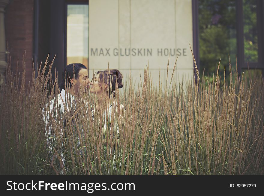 Man and Woman Kissing Near Green Plants