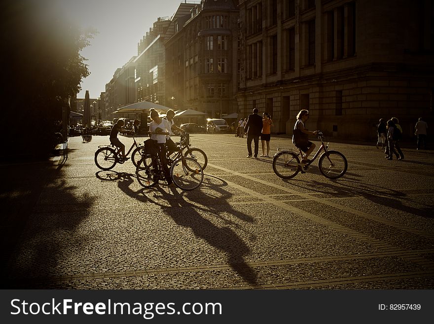 People on bicycles on city streets at sunset.