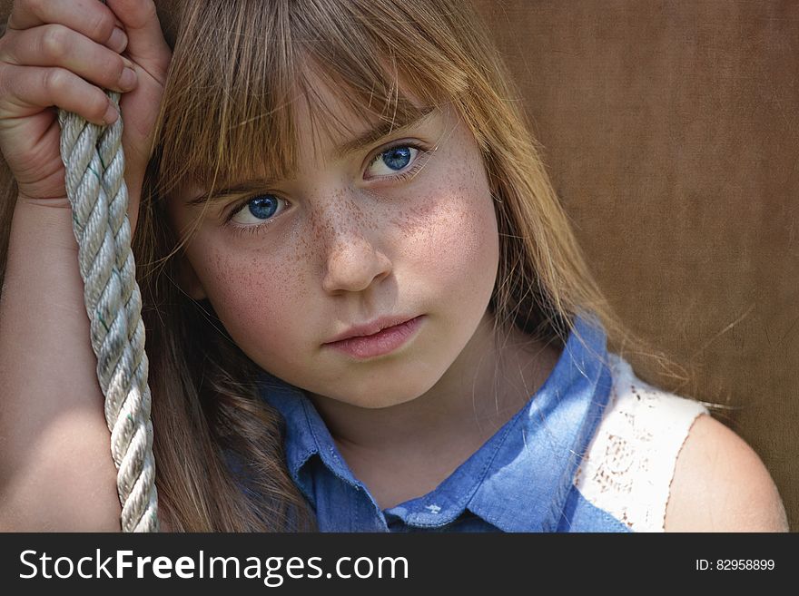 Young girl holding rope with thoughtful expression outdoors on sunny day. Young girl holding rope with thoughtful expression outdoors on sunny day.