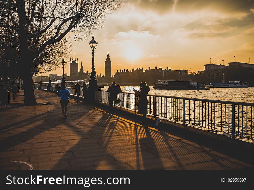 Pedestrians on waterfront along Thames River across from Westminster Abbey in London, England at sunset. Pedestrians on waterfront along Thames River across from Westminster Abbey in London, England at sunset.