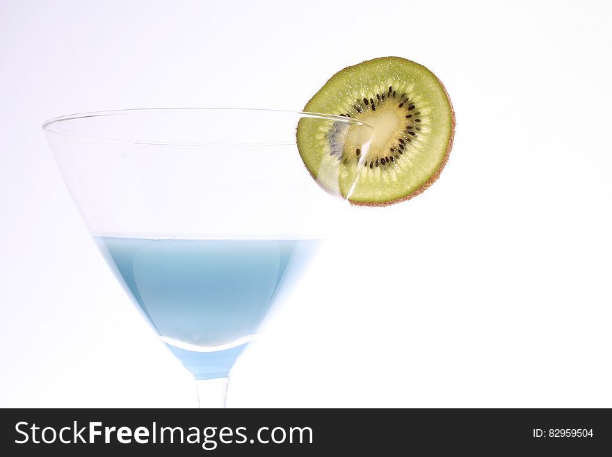 Blue liquid in martini glass garnished with slice of kiwi. Blue liquid in martini glass garnished with slice of kiwi.