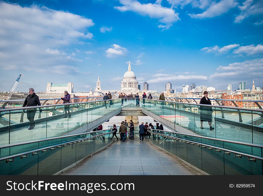 Pedestrians crossing the Millennium Bridge in London, England against blue skies on sunny day. Pedestrians crossing the Millennium Bridge in London, England against blue skies on sunny day.