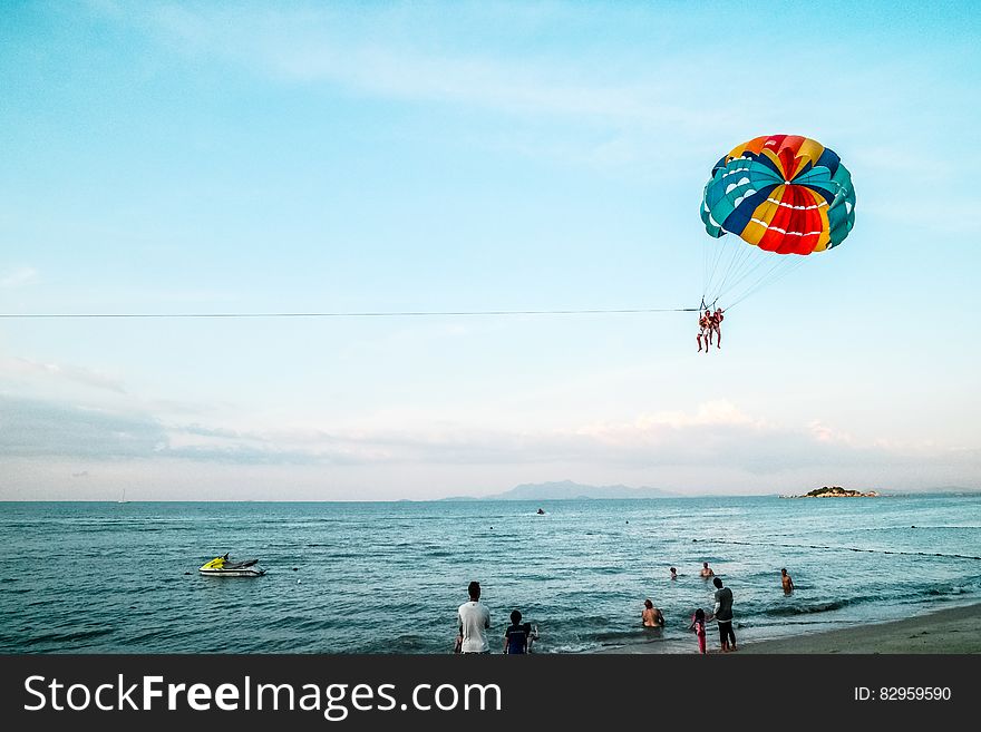 People Paragliding On Beach Over Sea