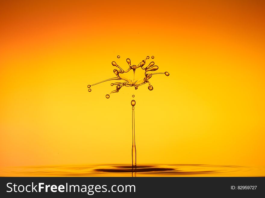 Close up of water droplet splashing against orange and yellow background. Close up of water droplet splashing against orange and yellow background.