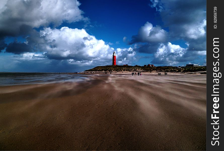 Lighthouse on sandy beach against blue skies with white clouds. Lighthouse on sandy beach against blue skies with white clouds.