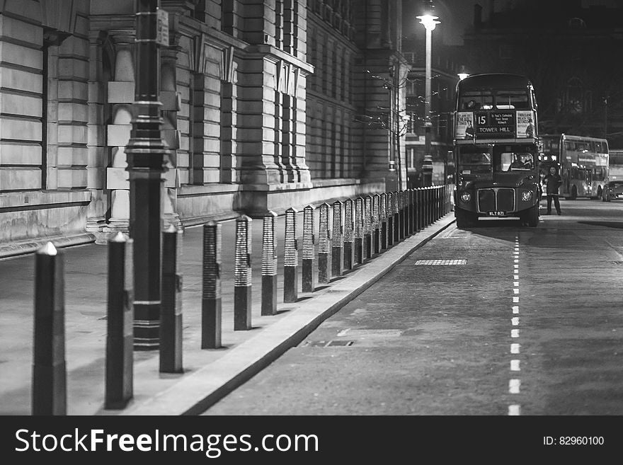 London double deck bus stopped in marked parking bay at night beside historic stone building. London double deck bus stopped in marked parking bay at night beside historic stone building.