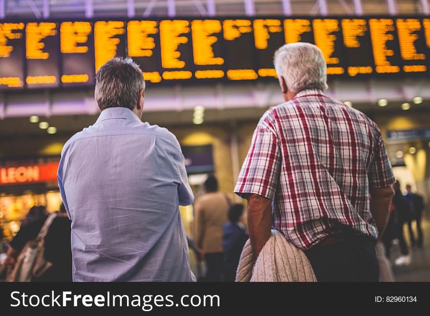 Man standing and looking at departure and arrival board inside modern airport or train station. Man standing and looking at departure and arrival board inside modern airport or train station.