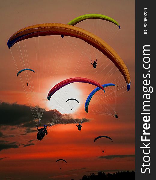 People Riding Parachutes During Sunset