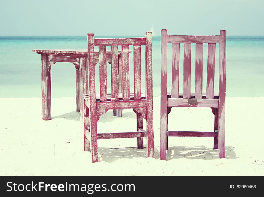 Wooden chairs and table on empty beach on sunny day. Wooden chairs and table on empty beach on sunny day.