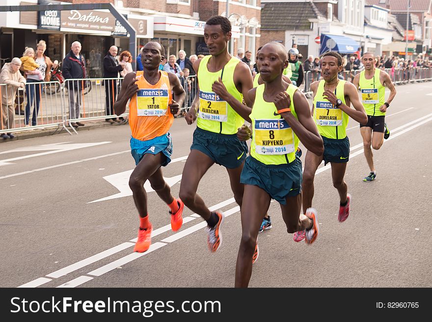 Marathon runners in pack on road race on sunny day.