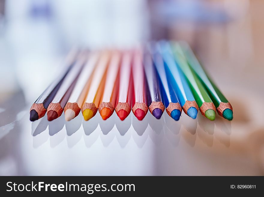 Row of colored pencil tips on glass table. Row of colored pencil tips on glass table.