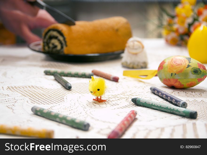 Table with crayons and decorated Easter egg with chick toy and dessert roll. Table with crayons and decorated Easter egg with chick toy and dessert roll.
