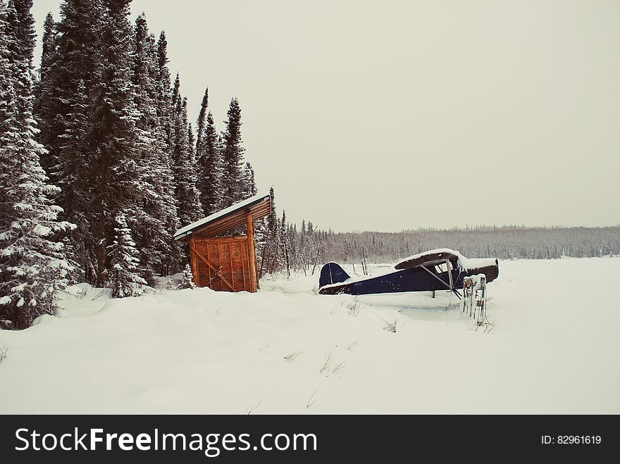 Black Aircraft Beside Brown Bunk House On Snowy Place