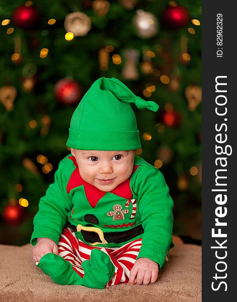 A young boy in Santa's elf costume with Christmas tree in background. A young boy in Santa's elf costume with Christmas tree in background.