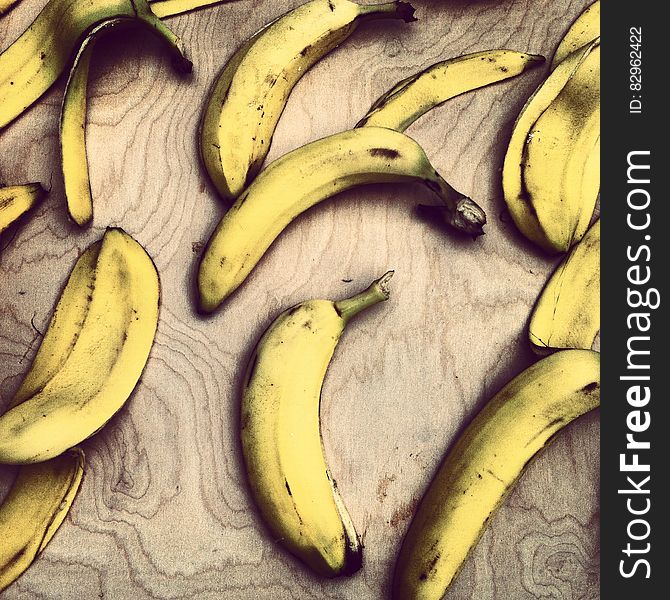 Background of over-ripe bananas and skins of eaten ones on a grainy wooden table. Background of over-ripe bananas and skins of eaten ones on a grainy wooden table.