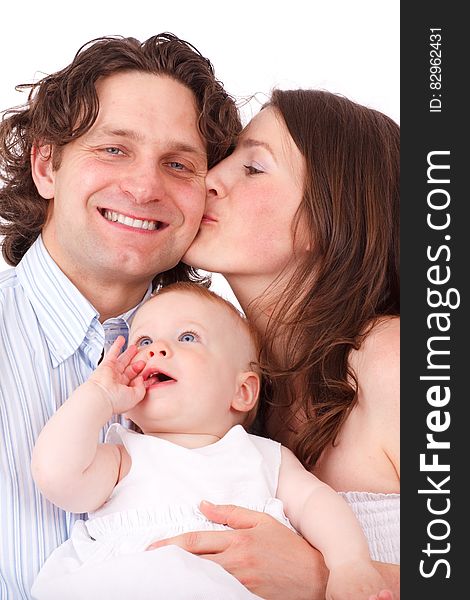 Brown Haired Woman Kissing Man In Blue White Dress Shirt Holding Baby In White Dress