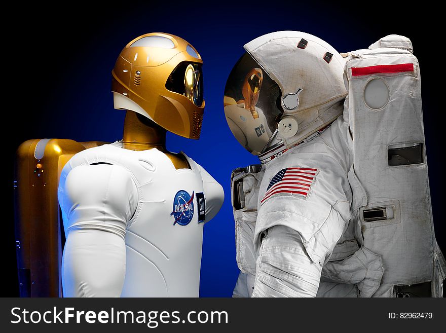 Human and robotic astronauts stood facing each other with different style equipment.