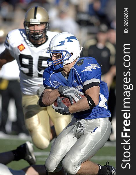 Man in Blue and Silver Football Uniform Carrying Football